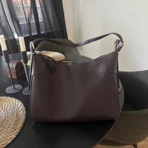 Mörkbrun axelväska i skinn - Säljer en stor brun väska från hm, aldrig använd så väldigt fint skick🩷 köpt för 500