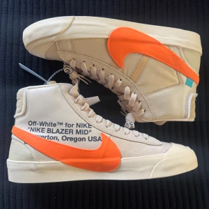 Off-White x Nike Blazer Mid Beige/Orange - Säljer ett par Off-White x Nike Blazer Mid med beige ovandel, stor orange Swoosh och klassisk Off-White-typografi på sidan. Extra laces ingår självklart. Kommer med originalkartong och papper. Helt nya, med tags på. Tar bud från 3500kr.