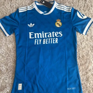 Blå Real Madrid Mbappé tröja Adidas M - Snygg blå Real Madrid fotbollströja från Adidas med Mbappé och nummer 10 på ryggen. 