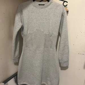 Grå sweatshirtklänning med markerad midja - Grå figursydd sweatshirtklänning från Bershka med markerad midja. 