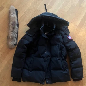 Svart dunjacka från C - Säljer en svart dunjacka från C i storlek S. Jackan har avtagbar huva med pälskant, klassisk patch på ärmen och rejäla fickor. Perfekt för kalla vinterdagar och har en riktigt puffig look.