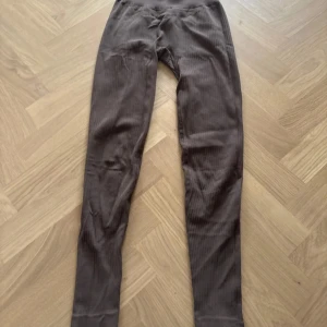 Bruna ribbade leggings XS/S - Snygga bruna leggings med ribbad struktur och hög midja. De är tillverkade i mjukt och stretchigt material med 96% polyamid och 4% elastan, vilket gör dem riktigt sköna att ha på sig. Perfekta för dig som gillar en slim och tight passform.