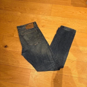  Denim & Supply Ralph Lauren -  Denim & Supply Ralph Lauren jeans med riktigt sjysst slitning på knät för mer design och eansen har slim/rak passform, normal midja och är tillverkade i 100% bomull. Storleken 33/32 men passar 32/32 