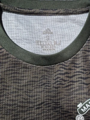 Manchester United bortatröja Adidas S - Säljer en Manchester United bortatröja från Adidas i storlek S. Tröjan har ett mörkgrönt och svart zebramönster, klassisk rund hals och korta ärmar. Materialet är lätt och andas, med Heat.RDY-teknologi. Loggor från Adidas, Manchester United och Chevrolet på bröstet.