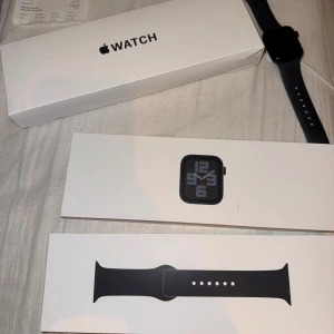 Helt ny Apple Watch SE Gen2 40mm midnight - Säljer en Apple Watch med svart silikonarmband och 40mm skärm. Klockan har en stilren, fyrkantig design med touchskärm och digital krona. Perfekt för att hålla koll på träning, notiser och hälsa. Levereras med originalförpackning med laddare. Helt ny. Kvitto finns, försäkring 1 år. Org pris 3400kr