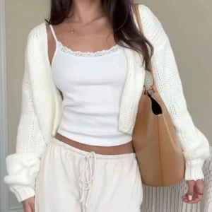 Vit stickad kofta med små knappar - Säljer en vit croppad stickad kofta med v-ringning och tre ljusa knappar framtill. Koftan har långa ärmar med lite loose passform och ribbade muddar. Så söt och perfekt för vintern och  att slänga över ett linne. (Inte exakt samma kofta som den första bilden)  Prislappen är bortklippt.