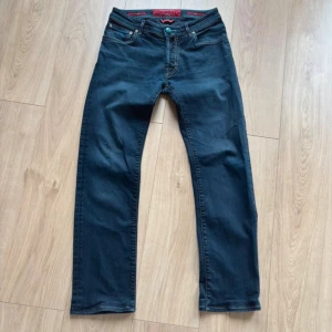 Mörkblå jeans från Jacob Cohën - Snygga mörkblå jeans från Jacob Cohën med klassisk femficksdesign och kontraststickningar. Jeansen har en rak passform och coola detaljer som blå broderad text på insidan. Handgjorda i Veneto, Italien. Perfekt för dig som gillar exklusiva jeans med unik touch.