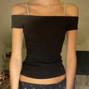 Svart offshoulder topp - Säljer en svart offshoulder topp med korta ärmar och tight passform😻Toppen har en stilren och enkel design utan mönster eller detaljer, perfekt att matcha med olika outfits!!Materialet känns mjukt och stretchigt. Storlek S, men passar också XS bra🤍Använd några gånger, har inga defekter! Från märket Weekday. Hör av vid funderingar❣️