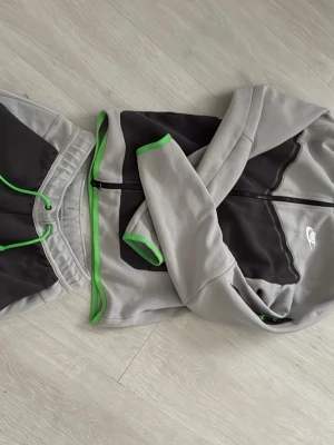 Nike Tech set limitid edition - Säljer ett Nike Tech Fleece set i limited edition, hoodie med dragkedja + matchande byxor. Snygg färgkombination i grått/svart med gröna detaljer som sticker ut. Svårt att få tag på denna modellen idag. Sälja endast som set 