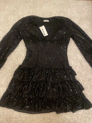 Svart paljettklänning från Meet Me There - Svart paljettklänning från Meet Me There i storlek M/L. Helt oanvänd, endast testat! Säljer pga att den var lite för kort för mig (är 172cm). Passar perfekt till nyår eller annan fest! Skickar så fort som möjligt 💕