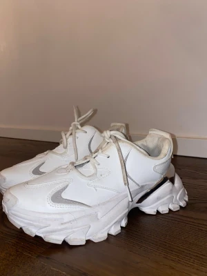 Chunky vita sneakers med silvrig detalj - Snygga vita chunky sneakers. Använda men i bra skick – normalt slitage syns på sulan. Bekväma att gå i och passar perfekt till vardag, jobb eller casual outfits.