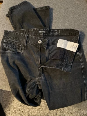 Svarta Replay jeans, storlek 31 - Säljer ett par svarta Replay jeans i klassisk femficksmodell. Jeansen har raka ben, snygga sömdetaljer på bakfickorna och Replay-lapp i midjan. Materialet är mjukt jeans-tyg som sitter skönt och passar till det mesta. Dragkedja i gylfen och bälteshällor.
