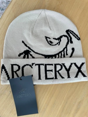 Arc’teryx Ascent Beanie – Beige – Aldrig använt! - Arc’teryx Ascent Beanie – Beige – Aldrig använt!  En stilren och funktionell mössa från Arc’teryx i beige med det klassiska logotrycket. Tillverkad i mjukt och slitstarkt material som håller dig varm både till vardags och vid utomhusaktiviteter. Aldrig använt, taggen sitter fortfarande kvar.  Arc’teryx Ascent Beanie – Beige – Never worn!  A clean and functional beanie from Arc’teryx in beige, featuring the classic logo design. Made from soft and durable material that keeps you warm for everyday 
