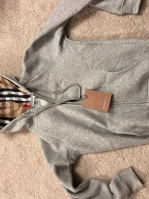 Bb tröja - Burberry zip up tröja med det kända rutiga mönstret. Mycket känd och stilrik tröja. Tröjan är storlek L men sitter absolut inte som L. Tröjan är max storlek S. 