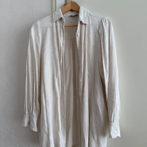 Beige skjorta från Stradivarius - Säljer en stilren beige skjorta i linne med klassisk krage och knäppning framtill. Superskön!