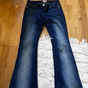 Blå bootcut jeans från Gina Tricot - Snygga mörkblå bootcut jeans från Gina Tricot med klassisk femficksdesign och lätt slitning på låren. Jeansen har normal passform och är tillverkade i stretchig denim för extra komfort. Perfekta för dig som gillar en retroinspirerad look.