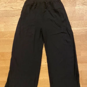 Svarta linnebyxor  - Svarta linnebyxor i storlek XS med resår i midjan. Byxorna har en avslappnad och vid passform, perfekta för en chill och stilren look. Tillverkade i 100% linne för en luftig känsla.