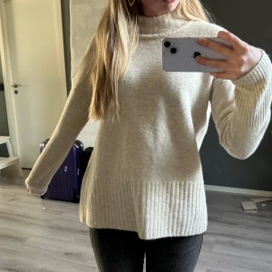 Beige stickad polotröja - Mysig beige stickad polotröja med ribbade detaljer vid hals, ärmslut och nederkant. Tröjan har en loose passform och är perfekt för kyliga dagar. Köpt för längesedan men aldrig använd.