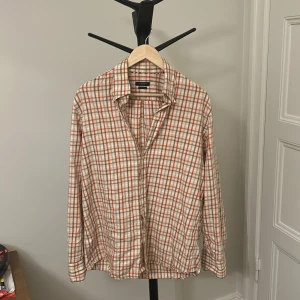 Rutig vintage slim fit skjorta från Burberry - Snygg rutig skjorta från Burberry London i slim fit-modell. Skjortan har klassiskt beige, orange och brunt rutmönster, långa ärmar och knappar framtill. Strlk 41 vilket motsvarar Large