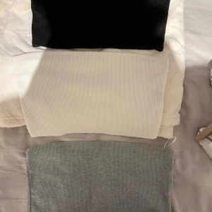 3-pack ribbade tubtoppar från SHEIN - Säljer ett 3-pack ribbade tubtoppar från SHEIN i storlek M. Färgerna är svart, vit och grå. Alla topparna är bandeau-modell och ärmlösa, perfekta att styla med jeans eller kjol. Materialet är mjukt och stretchigt för en bekväm passform. Passar S oxå. 