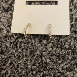 Glittriga silvriga hoops örhängen - Säljer ett par små silvriga hoops med glittriga stenar längs hela ringen. Är inte helt säker på vart dem kommer k från men tror h&m så alltså vet jag ktne ny pris,