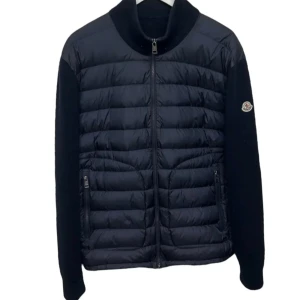 Svart Moncler pufferjacka med dragkedja - Snygg svart pufferjacka från Moncler med quiltad framsida och stickade ärmar. Jackan har hög krage, två fickor med dragkedja och Moncler-logga på ärmen. Perfekt för dig som vill ha en stilren och exklusiv look under kyliga dagar. Liten i storlek!!!!!!