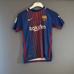 FC Barcelona Messi 10 matchtröja  - Säljer en äkta FC Barcelona matchtröja med Messi . Tröjan är blå med röda ränder, har korta ärmar och är tillverkad i lätt Dri-FIT-material. , klubbmärke och sponsorer på bröstet. Perfekt för dig som älskar fotboll och Messi!