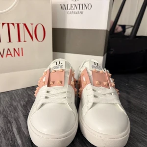 Valentino sneakers  - Trendiga Valentino sneakers i storlek 39! Vita med rosa detaljer som lyfter varje outfit. Perfekt för både vardag och fest. Ett måste för dig som vill ha både stil och lyx i samma sko. Helt nya! 🌸