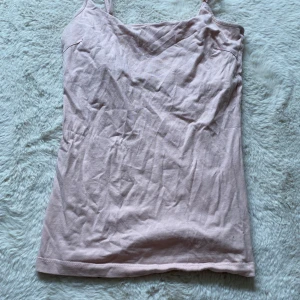 Ljusrosa linnetopp med smala axelband - Säljer en enkel och stilren ljusrosa linnetopp med smala axelband. Toppen är ärmlös och har en rak passform, perfekt för varma dagar. Tillverkad i mjuk bomull som känns skön mot huden.