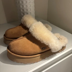 UGG tofflor W Disquette  - Mysiga tofflor från UGG i färgen chestnut, storlek 39. Jätte sköna och mysa men tyvärr så tycker jag att dom inte passar mig. Dom är använd några fåtal gånger men i väldigt fint skick. nypris ca 1600 