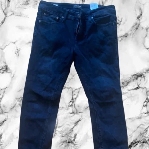 Mörkblå jeans från Jack & Jones - Snygga svarta jeans från Jack & Jones med klassisk femficksdesign och raka ben. Jeansen har en normal passform och är tillverkade i ett slitstarkt bomullsmaterial. Perfekta för dig som gillar en enkel och stilren look.