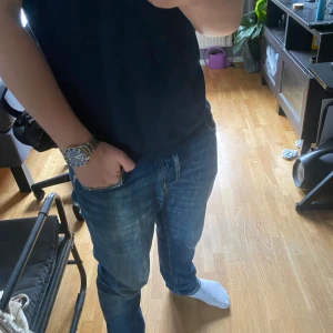 Blå jeans från Jacob Cohen - Säljer ett par snygga blå jeans från Jacob Cohen med coola färgade sömmar på bakfickorna och klassisk läderpatch. Jeansen har normal passform och raka ben, tillverkade i mjukt bomullsjeans-tyg. Perfekta för dig som gillar stilrena men ändå unika detaljer. Jeansen har ett hål på höger knä. Men det tycker jag är snyggt. Jeansen har otroligt material! 