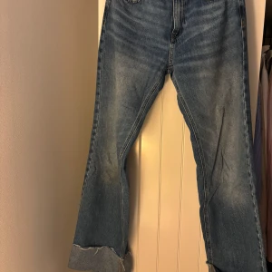 Blå jeans från Vero Moda - Snygga blå jeans från Vero Moda med rak/vid passform och råa, uppvikta benslut. Klassisk femficksmodell med medel midja och ljus tvätt. Perfekta för dig som gillar en avslappnad men trendig look.