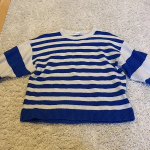 Randig blåvit stickad tröja Name It - Randig stickad tröja från Name It i blått och vitt. Tröjan har en klassisk rund halsringning och långa ärmar. Perfekt för dig som gillar en chill och stilren look med lite marint vibe. 40kr med frakt!📦 