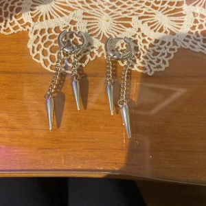 Silvriga örhängen  - Coola silvriga örhängen med ringformad bas och två hängande kedjor med spetsiga spikes. Knappt använda. Säljs som ett par.