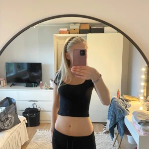 Svart croppad topp från H&M Divided - En svart, croppad topp från H&M Divided med rund halsringning och korta ärmar.