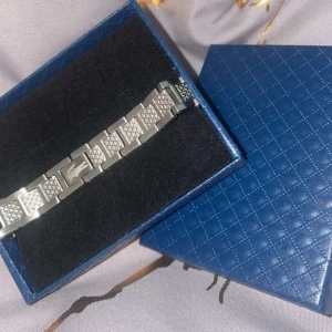 Silverfärgat armband från Lacoste - Stilrent armband i silverfärg från Lacoste med klassisk krokodil-logga. Länkarna har ett rutigt mönster som ger en cool och modern känsla. Kommer i en snygg svart ask istället gör den blå i bilden. Helt ny har köpt den till min son men den var lite förstor. Pris kan diskuteras!