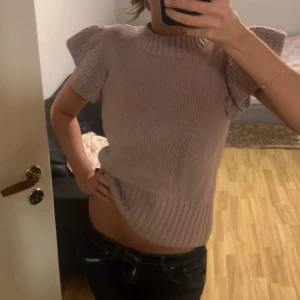 Beige stickad topp från Holly & Whyte - Supersöt stickad topp i ljusrosa från Holly & Whyte. Modellen har korta ärmar med volangdetalj och ribbad struktur vid hals och nederkant. Supersnygg med både jeans och kjol! Köptes från Lindex för 800kr, nästan aldrig använt men har fått så många komplimanger när jag haft på mig den❤️❤️ 