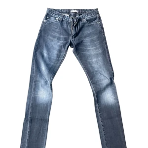 Mörkblå jeans från Acne Studios - Snygga blå jeans från Acne Studios med klassisk femficksdesign och orange läderpatch bak. Jeansen har raka ben och normal passform, tillverkade i slitstarkt denimtyg. Perfekta för dig som gillar stilrena och tidlösa jeans med en modern touch.