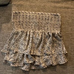 Volangshorts med leopardmönster - Supersöta shorts med volanger och smockad midja. Beige botten med svart leopardmönster ger en trendig look. Perfekta för varma dagar och riktigt sköna att bära tack vare det lätta materialet. Den är även jättefin som en topp.