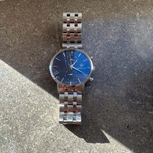 Gant klocka i herrmodell. - Gant klocka i herrmodell. Spännet är lite snett men går fortfarande att stänga. Byte av batteri behövs 