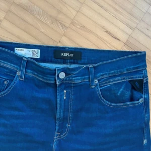 Blå Replay jeans i slim fit - Säljer ett par blå jeans från Replay med klassisk femficksdesign och snygga kontrastsömmar. Jeansen har smal passform och normal midja, tillverkade i stretchigt denim för extra komfort. Perfekta för dig som gillar stilrena och moderna jeans.