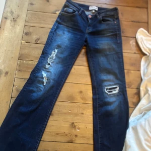 Mörkblå jeans från ONLY - Snygga mörkblå jeans från ONLY med slitna detaljer på benen. Jeansen har råa, fransiga benslut och klassisk femficksdesign. Perfekta för dig som gillar en avslappnad och trendig look. Har sprätt upp dem vid fötterna