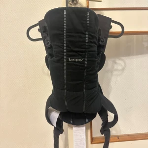 Svart BabyBjörn bärsele mini - BabyBjörn bärsele mini är använd men fortfarande i fint skick. Passar redan från nyfödd