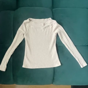 Ribbad beige långärmad tröja Lindex - Säljer en ribbad beige långärmad tröja från Lindex. Tröjan har en bredare halsringning och är i mjukt, stretchigt material som sitter snyggt på kroppen. Perfekt att styla med jeans eller kjol för en clean look.