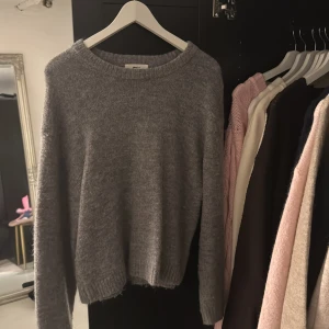 LjusGrå stickad tröja från Gina Tricot - Mysig ljusgrå stickad tröja från Gina Tricot i ullblandning. Tröjan har rund halsringning, ribbade muddar och en klassisk, enkel design som är lätt att matcha. Perfekt för lager-på-lager under kyliga dagar. Använt ett fåtal gånger 