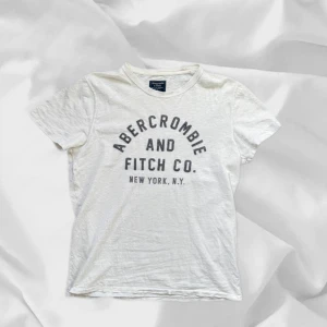 Abercrombie & Fitch T-Shirt - Fet t-shirt från A&F i storlek M – enkel att matcha och skön att bära. Ett stilrent val, noggrant utvalt med omsorg av AM Clothing.  📩 Frågor? Hör gärna av dig! 📲 Följ oss här på Plick för fler uppdateringar. ♻️ Tack för att du handlar mer hållbart med AM Clothing!