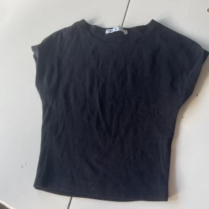 Svart croppad topp från Zara - En svart croppad topp från Zara med rund halsringning och korta ärmar. Enkel och stilren design i mjuk bomull, perfekt att matcha med jeans eller kjol. Snygg basic som funkar till många olika looks.