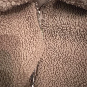 Beige teddyjacka från H&M L.O.G.G. - Mysig beige teddyjacka från H&M L.O.G.G. i storlek M. Jackan har en fluffig och mjuk yta, klassisk krage och hel dragkedja framtill. Perfekt för kyliga dagar när du vill ha en chill och trendig look.