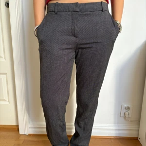 Lågmidjade grå kostymbyxor med diskret mönster - Använts en gång. Grå kostymbyxor med diskret rutigt mönster och klassisk rak passform. Byxorna har hällor för bälte, sidofickor. Köpta på HM för flera år sedan. 